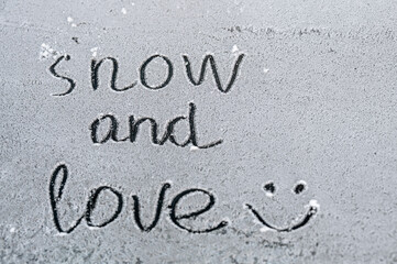 The inscription "snow and love" on the snow with a smiley. Fresh white snow covered the ground. Rest, walk in the fresh air. December, January, February.