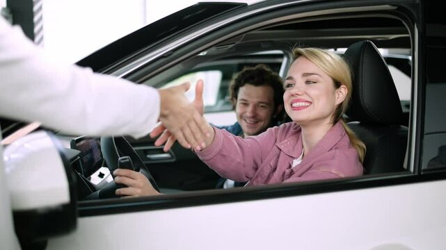 A couple examines options for a new family car in a modern showroom. Their careful selection reflects the importance of finding a vehicle that meets both lifestyle needs and family comfort.