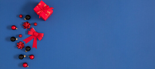 Christmas modern composition on dark blue background. Red and black Christmas decorations balls, gift. Top view, banner