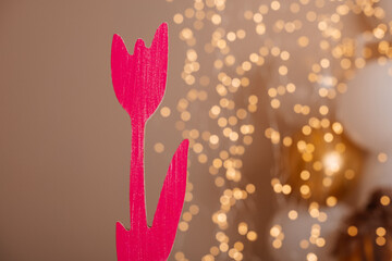 A bold red wooden tulip against a blurred, sparkling light background, bringing both nature and festive vibes together.