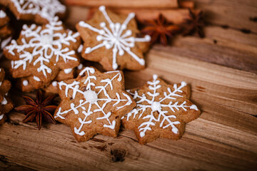 Gingerbread cookies with white snowflake icing, arranged with star anise on a rustic wooden surface, creating a cozy and festive holiday atmosphere.