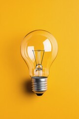 A vintage light bulb placed against a vibrant yellow background for aesthetic appeal