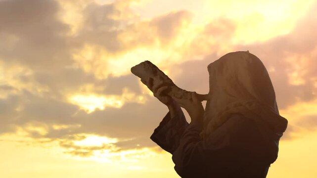 the silhouett of  Jewish man blowing the Shofar horn of Rosh Hashanah New Year  on sunset