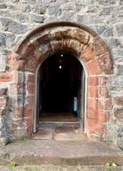 Dalton Castle, England. A weathered stone archway leading into a darkened interior, framed by...