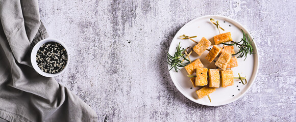 Pieces of delicious fried tofu soy cheese on skewers on a plate on the table top view web banner