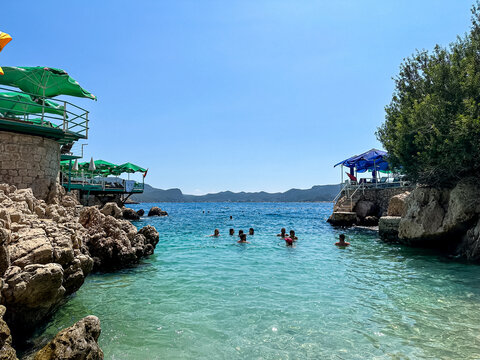 Kas, T&uuml;rkiye - 02.09.2024. Kucuk Cakil Beach view. Tourists enjoying wild beach with lots of sunbeds and umbrellas on the sides. Summer in turkey. Turquoise water