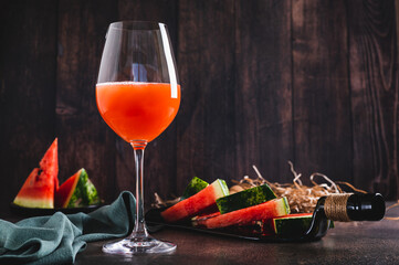 Delicious watermelon wine in a glass and watermelon pieces on a plate on the table