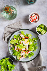 Appetizing salad of crab sticks, cucumber, leaves and egg on a plate top and vertical view