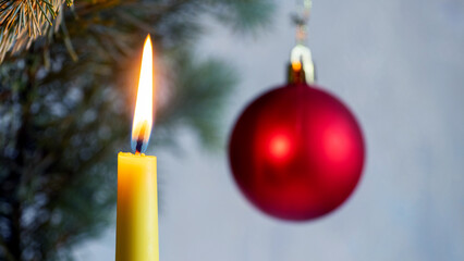 Christmas and New Year card with lit candle and red ball near the Christmas tree