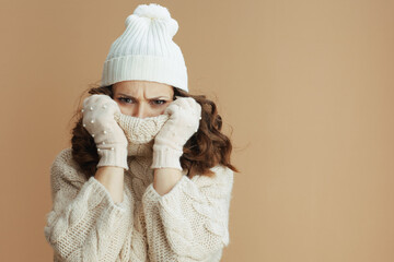 sad stylish woman isolated on beige wrapped in collar