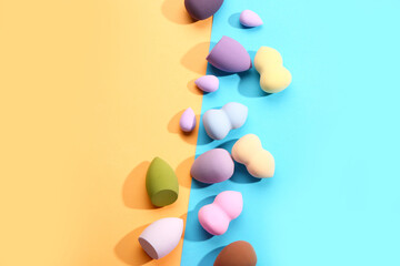 Different makeup sponges on colorful background
