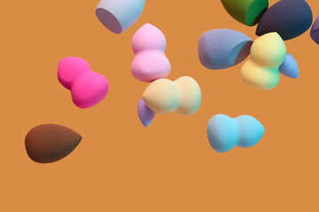 Flying different makeup sponges on orange background