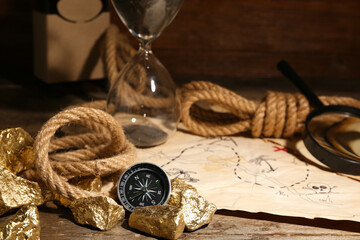 Travel equipment with treasure map and golden nuggets on brown wooden background