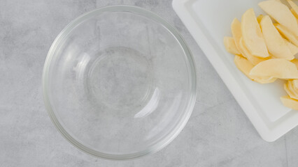 Apple cake recipe. Sliced apples on a cutting board, and a glass bowl close-up on a kitchen table