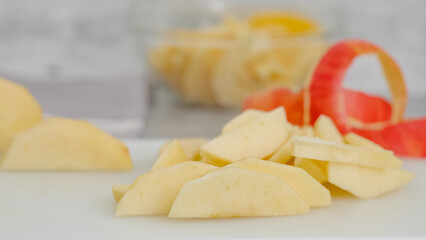 Apple slices, and apple peel close-up on a white cutting board on the kitchen table