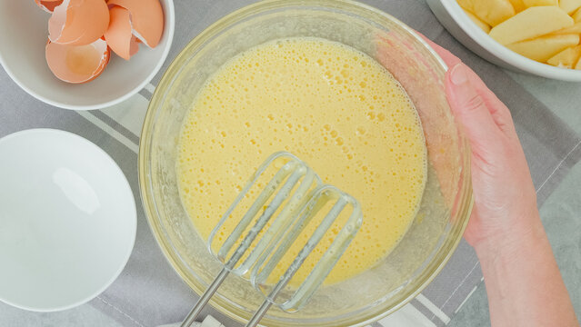 Egg and sugar mix in a glass bowl close-up on a kitchen table. Apple cake recipe, flat lay - Powered by Adobe