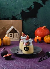 Dessert, pumpkin panna cotta with chia pudding and fresh figs in portioned jars in Halloween design...