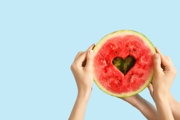 Women holding slice of ripe watermelon with heart on blue background