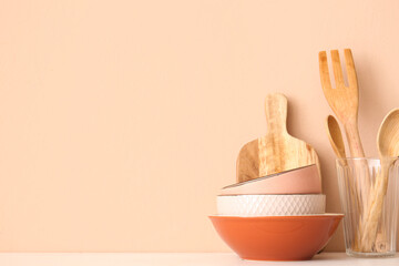Kitchen utensils and bowls on wooden table near beige wall