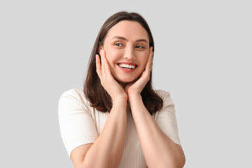 Fototapeta premium Smiling young woman on grey background