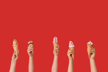 Female hands with different sweet ice-cream in waffle cones on red background