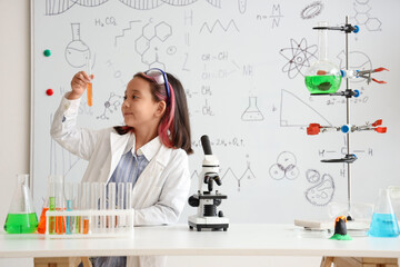 Cute little girl with scientific equipment in chemistry classroom