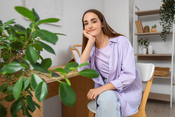 Young pretty woman sitting at table at home