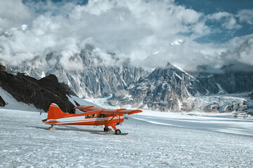 Red plane landing on a glacier in Denali mountains. Winter expedition.