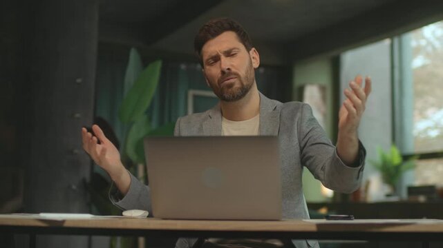 Upset disappointed young Caucasian man closing laptop after exhausting work. Guy holding hand over head. Headache concept. Camera moving around. Parallax effect. Optical illusion. Negative emotions