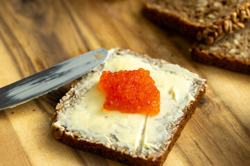 a sandwich of black bread, butter and red salmon caviar