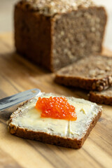 a sandwich of black bread, butter and red salmon caviar