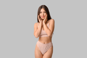 Naklejka premium Beautiful young happy Asian body positive woman in underwear on grey background