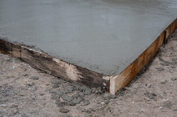 Wet concrete pouring into wooden frame