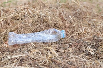 An empty of plastic drinking bottle littering on dried grass in outdoor for green environmental cleaning concept 