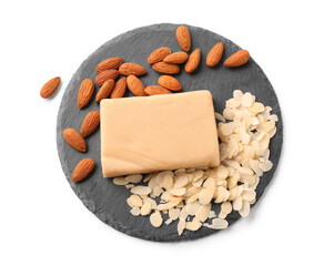 Slate board with tasty marzipan bar, almond nuts and flakes on white background