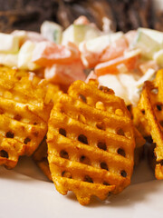 Cooked potato chips fries in a lattice shape on a white plate. Selective focus. Marketing move to sell popular product with increased price for higher profit by just changing the look.