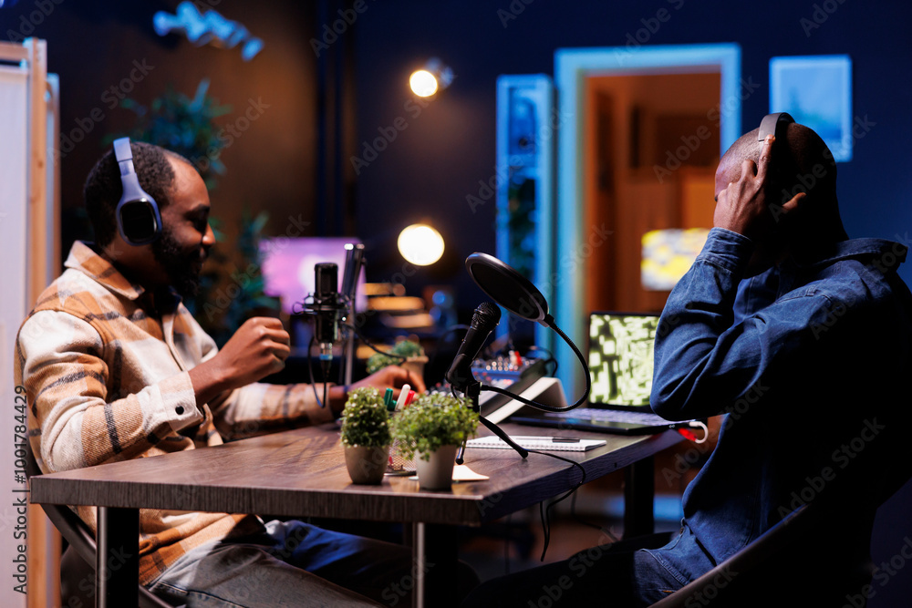 Poster young interviewer adjusting the sound mixer while talking with guest, recording a talk show. two afr
