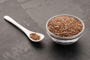 Organic dried flax seeds in bowl and spoon - Linum usitatissimum.