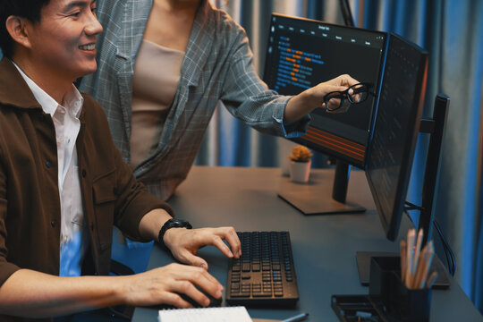 IT developers discussing with point to intelligent website development coder system running data online two screens information technology at neon light room at modern office. Infobahn.