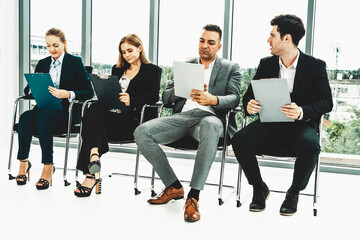 Businesswomen and businessmen holding resume CV folder while waiting on chairs in office for job interview. Corporate business and human resources concept. uds