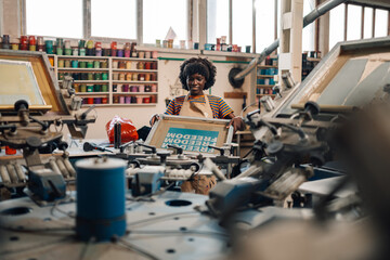 Happy diverse printing shop worker operating printing machine at facility