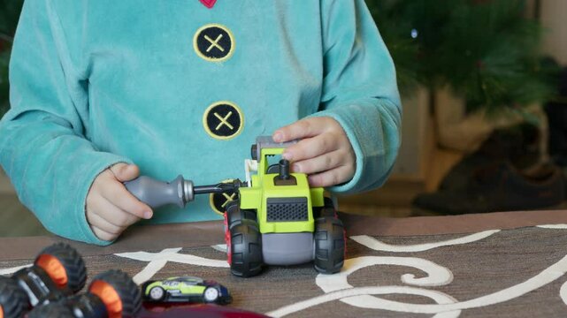 Cute boy elf assembling toys for kids in front of Christmas tree. High quality 4k footage