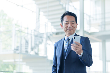 空港でスマートフォンを使う中高年のビジネスマン