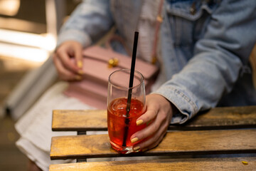 Woman holding a cup with a red iced drink with a straw
