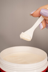 close up of a hand holding a spoon with face and body scrub