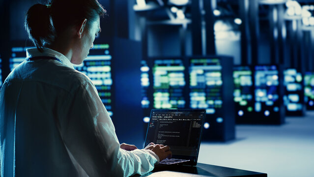 Certified admin running code and programming on laptop, troubleshooting and upgrading server hub equipment designed to accommodate rackmounts, networking systems and storage arrays