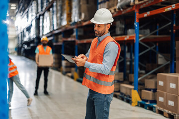 Focused warehouse worker analyzing tasks on digital tablet