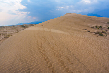 Dramatic desert dunes under sunbeams and cloudy sky