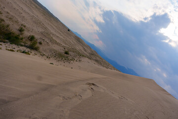 Dramatic desert dunes under sunbeams and cloudy sky