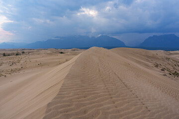 Dramatic desert dunes under sunbeams and cloudy sky